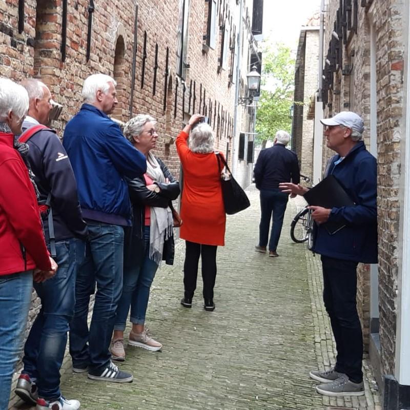 In een steeg van Harlingen krijgen bezoekers van Monumentendag uitleg van een gids.